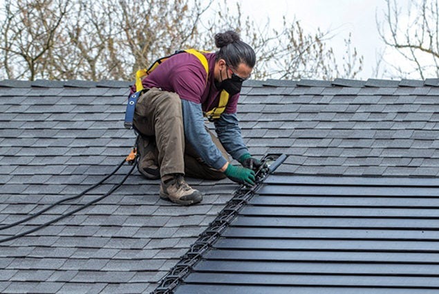 Man installing GAF solar shingles on a home