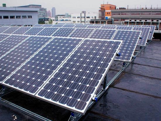 Multiple rows of solar panels on a roof in a city setting