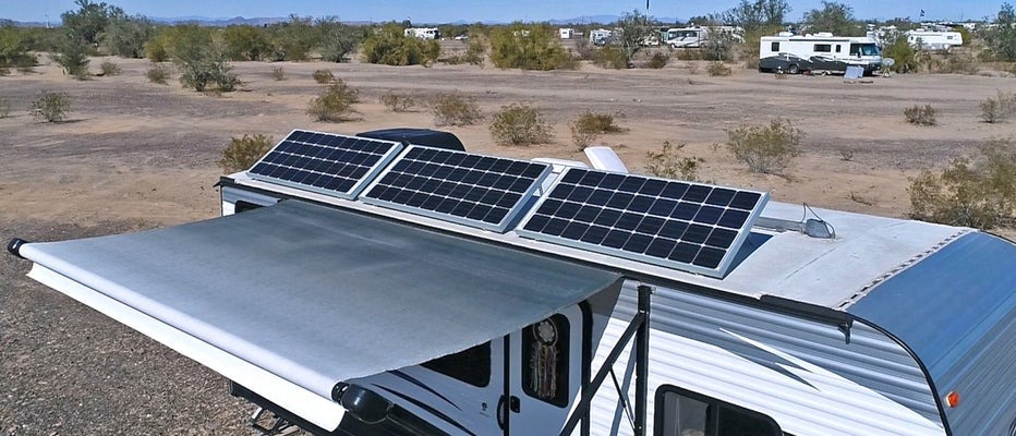 photo of an RV with solar panels on its roof and a rollout awning